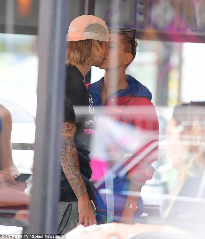 "Hoàng tử nhạc pop" và hôn thê xinh đẹp trao nhau nụ hôn trong một cửa tiệm.